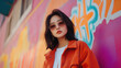© NaphakStudio - Young Asian woman in sunglasses poses confidently in front of colorful mural, showcasing vibrant urban style and dynamic expression