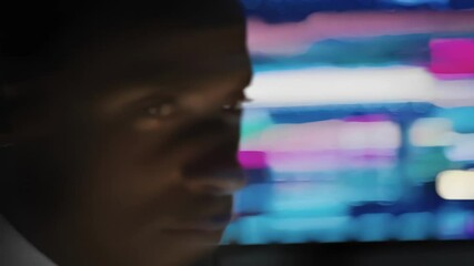 Poster - Two businessmen, one caucasian and one african american, attentively observe stock market data displayed on multiple screens in a dark room