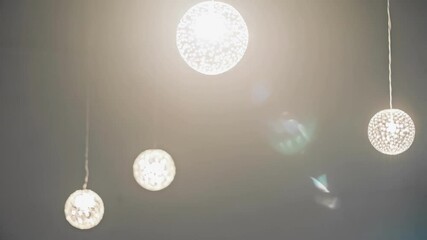 Aufkleber - Several modern spherical light bulbs are swinging gently, creating a mesmerizing dance of light and shadow in a contemporary interior space