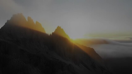Aufkleber - Golden sunlight bathes towering mountain peaks, casting long shadows over a sea of clouds, while a tranquil lake mirrors the breathtaking transition from darkness to dawn