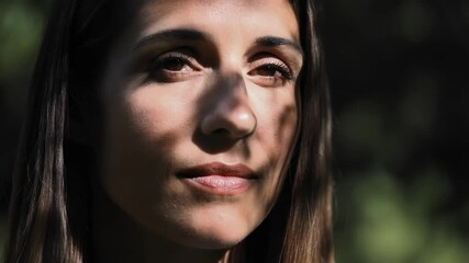 Poster - Natural light filters through leaves, casting intriguing shadows across a woman's face as she gazes serenely into the distance, creating a captivating portrait