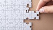 © ADD PHOTO - Hand carefully placing the final piece to complete a jigsaw puzzle representing problem solving strategic thinking and determination to achieve a goal