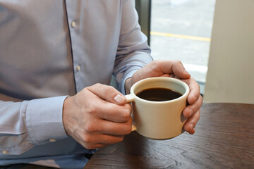 Wall Mural - Businessman having coffee break at wooden table in cafe, closeup