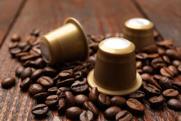 Wall Mural - Coffee capsules and beans on wooden table, closeup