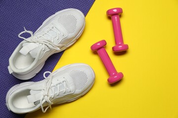 Wall Mural - Dumbbells, fitness mat and sneakers on yellow background, flat lay. Space for text