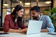 © SimpleDesignStudio - A young South Asian woman and man collaborating on a laptop in a modern office setting, showcasing teamwork and creativity in a bright workspace.
