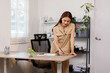 © David - Portrait of a smiling young Asian business woman leaning on her desk in a large modern office working online with a digital tablet