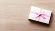 © Edo - White Gift Box with Pink Ribbon on Wooden Background