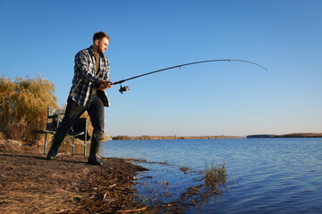 Wall Mural - Fisherman with rod fishing at riverside. Recreational activity