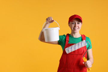 Wall Mural - Professional painter with roller and bucket of paint on orange background. Space for text