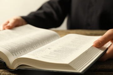 Wall Mural - Woman with Holy Bible in English language at wooden table, closeup