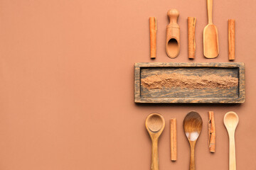 Wall Mural - Wooden board with cinnamon powder, sticks, spoons and scoops on color background