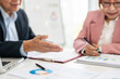 © Fahng - Business people working together. Serious businessman talking to businesswoman with papers and pen. Business partners having successful meeting in modern office..