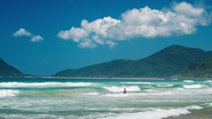 Sticker - Mountain and waves in Brazil with people swimming in the ocean on the foreground