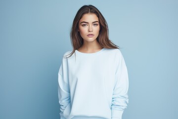 Wall Mural - A woman is wearing a blue sweater and standing in front of a blue wall