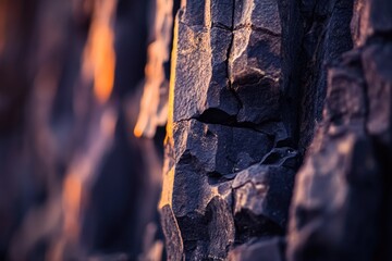 Wall Mural - Close-up of dark, rugged rock formations at sunset, showcasing texture and depth.