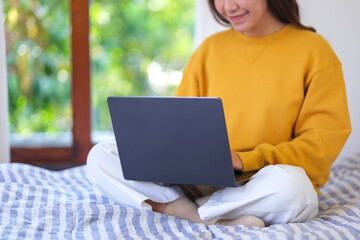 Wall Mural - closeup of a woman using and working on laptop computer while sitting on bed