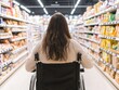 © JP STUDIO LAB - Young woman in a wheelchair shopping in a grocery store, demonstrating accessibility in public spaces and independent living