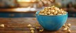 © Ahmad - Close up view of a vibrant blue bowl filled with peanuts on a rustic wooden table with blurred background and ample copy space available