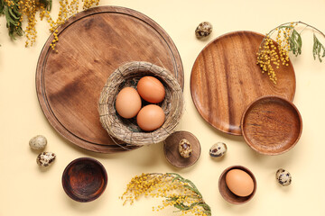 Wall Mural - Table setting with Easter eggs, nest, trays and plants on light yellow background