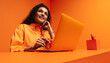 © Jacob Lund - Pensive woman working on a laptop in a vibrant, monochromatic orange office space