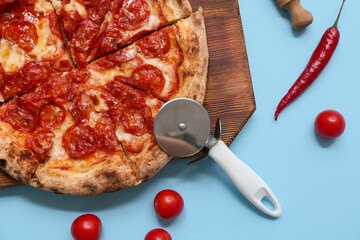 Wall Mural - Composition with tasty pizza, ingredients and cutter on blue background