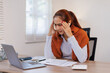 © David - Shot of sad young asian woman overthinking while holding laptop computer and mobile phone sitting on the sofa at home