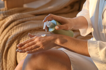 Wall Mural - Young woman applying cream onto her hand in bedroom, closeup