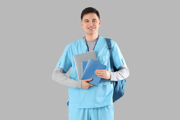 Poster - Male medical intern with backpack and notebooks on grey background