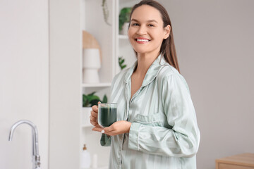 Sticker - Young woman with cup of spirulina drink in bathroom