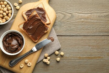 Wall Mural - Sandwiches with chocolate butter, hazelnuts and knife on wooden table, flat lay. Space for text