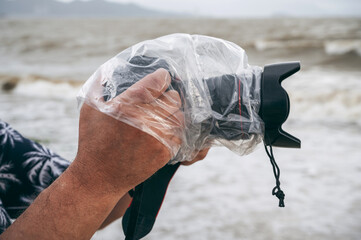 digital camera in waterproof case and a protective plastic bag against rain splashes in male hands o
