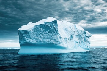 Poster - An iceberg floating in the ocean under a cloudy sky, great for use in climate change or environmental awareness scenes