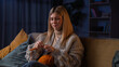 © kinomaster - Woman spending evening at home with hobby crafting, sitting on the sofa and knitting scarf, using colorful wool yarn and needles, positive expression.