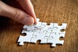 © photopixel - Hand placing puzzle piece on wooden table (9)