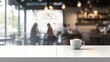 © CC - Sleek white rectangular wooden table with bright lighting and blurred chic cafe background featuring customers and coffee cups