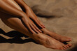 © Mirrorstudio - Tanned female legs and sand highlighting sun-kissed skin. Skin care, sun protection
