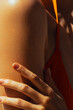 © Mirrorstudio - Close-up of female with sunlit skin and orange garment on shoulder. Skin care, sun protection