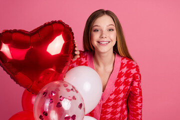 Wall Mural - Charming young woman with balloons in heart-themed setting, smiling brightly, celebrating with joy and a stylish red and pink outfit