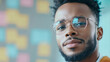 © Michael - Close-up portrait of a confident young manager wearing eyeglasses posing in front of colorful notes wall in the office