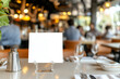 © photo for everything - Table setting in a restaurant with blank menu card, silverware, and glassware on a white tablecloth. Soft lighting and a blurred background of patrons.
