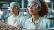 © Michael - Two young factory workers wearing hairnets, aprons and protective goggles are inspecting a production line of roasted coffee beans