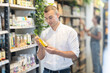 © JackF - Attentive young male buyer making choice holding bottle of care product in cosmetic store