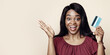 © Prostock-studio - Joyful afro-american long-haired young lady holding credit card and cheerfully smiling at camera on beige studio background, going for shopping or celebrating salary day, closeup photo
