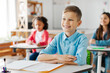 © Home-stock - Happy smart schoolchildren listening carefully to teacher at the lesson, sitting at desks in classroom, focus on smiling boy. New academic semester year or end of educational year