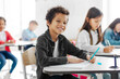 © Home-stock - Happy Latin boy sitting at desk in classroom, learning, writing in notebook, preparing for final exam test or project, smiling at camera