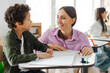 © Home-stock - Friendly teacher helping Latin boy and talking to him, sitting near his desk in elementary school. Support, scholarship and educator aid