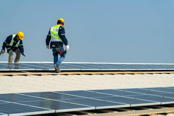 Wall Mural - two engineers install solar panels on a rooftop, wearing safety gear and helmets. the scene showcase