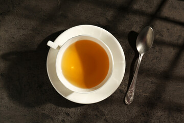 Wall Mural - Refreshing green tea in cup and spoon on dark textured table, top view