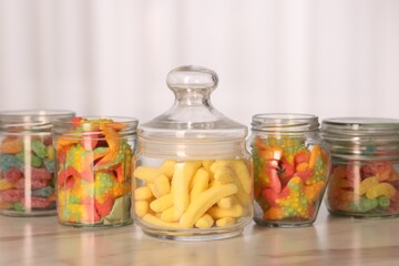 Wall Mural - Tasty gummy candies in glass jars on white marble table, closeup